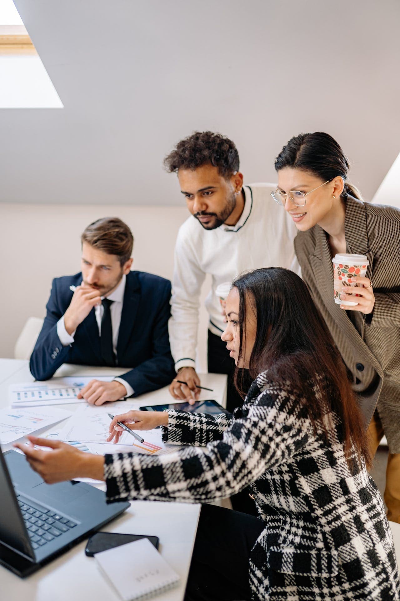 Ein diverses Expertenteam analysiert gemeinsam Daten und Workflows an einem Laptop, um eine professionelle Atlassian-Beratung durchzuführen