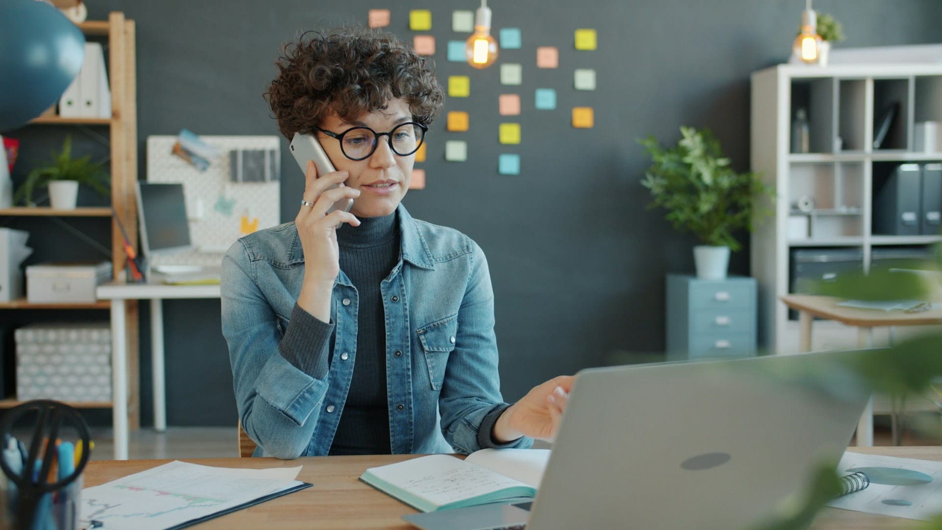 Mitarbeiterin im technischen Atlassian Support am Laptop und Telefon für eine schnelle Lösung von Störungen im Tagesgeschäft